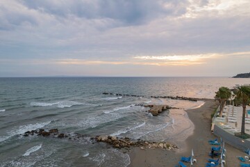 A peaceful beach in Chalkidiki at dusk. The ocean gently laps against the sandy shore, with palm...