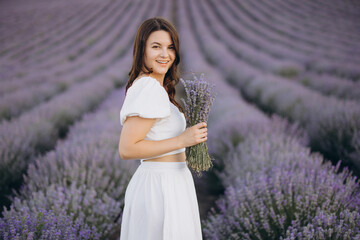 Woman wearing white dress holding lavender bouquet in a lavender field