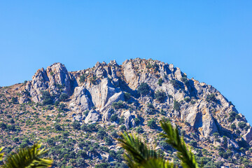 Rocky mountain peak with sparse vegetation under clear blue sky on sunny day. Kos. Greece.