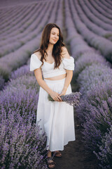 Woman wearing white dress holding lavender bouquet in lavender field