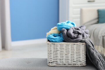 Soft felting wool in wicker basket on ottoman indoors, closeup. Space for text
