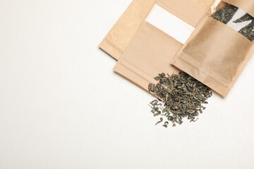 Zipper stand-up pouches and dry leaves on white table, flat lay. Mockup for design
