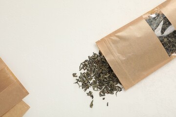 Zipper stand-up pouches and dry leaves on white table, flat lay. Mockup for design