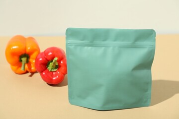 Zipper stand-up pouch and bell peppers on beige table, closeup. Mockup for design