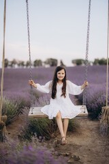 Young girl swinging in a lavender field during a summer day