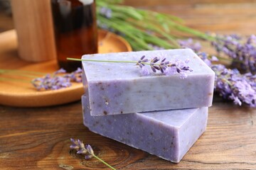 Soap bars, other cosmetic products and lavender flowers on wooden table, closeup