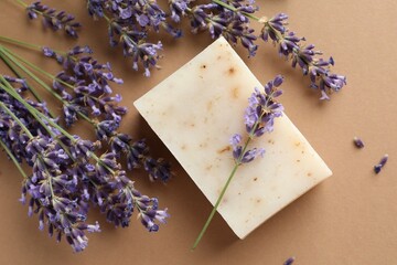 Aromatic soap bar and lavender flowers on beige background, flat lay