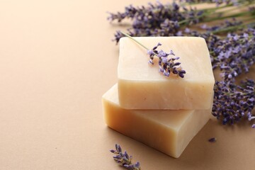 Aromatic soap bars and lavender flowers on beige background, closeup. Space for text