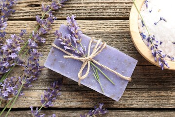 Aromatic soap bar, lavender flowers and sea salt on wooden table, flat lay