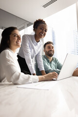 Group of happy diverse professionals collaborate in office, gathered at conference table with documents and laptop, smiling, looking away. Teamwork, innovation, and digital productivity, vertical shot