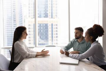 Female applicant passes job interview seated at table in front of two pensive or skeptical HR managers listen her answers regarding education and skill, feel undecided or doubtful about her knowledges