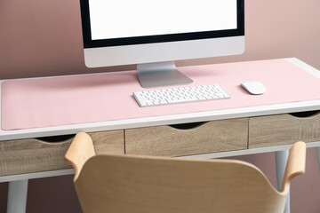 Fototapeta premium Stylish workplace with computer and pink mousepad on white table indoors. Space for text