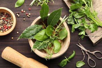 Mortar with different fresh herbs and peppercorns on wooden table, flat lay