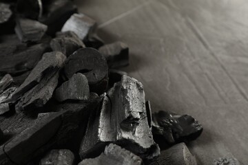 Pieces of black coals on grey table, closeup. Space for text
