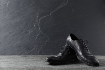 Pair of black leather shoes on grey surface, space for text