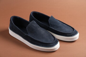 Pair of dark blue shoes on dark beige background, closeup