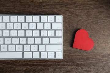 Decorative heart and computer keyboard on wooden table, flat lay. Online dating site