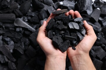 Man with black coals over pile, top view