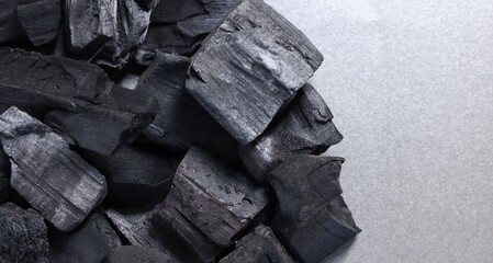 Pieces of black coals on grey table, top view. Space for text