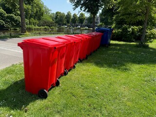 Many color trash bins on green grass in park, space for text