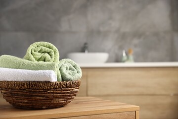 Fresh terry towels on wooden table in bathroom. Space for text