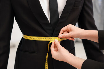 Tailor measuring jacket on man in atelier, closeup