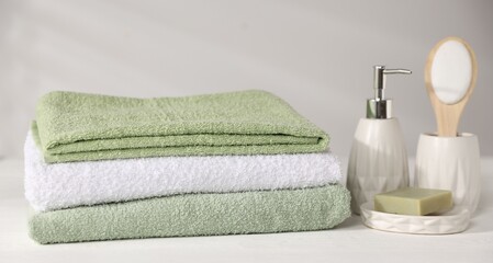 Fresh terry towels and cosmetic products on white wooden table
