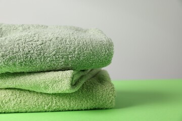 Fresh terry towels on green table, closeup