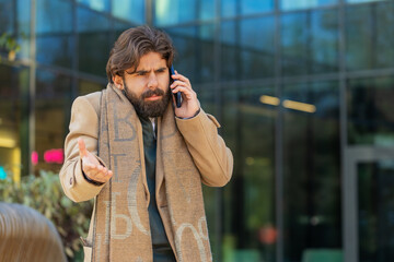 Angry Indian business man arguing while talking on smartphone while walking in downtown city...