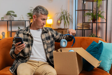 Unhappy young Caucasian man guy unpacking carton box, feeling dissatisfied with getting damaged...