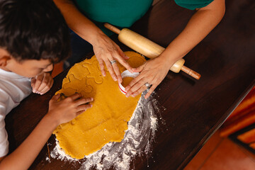 Unrecognizable Latin woman and teenage boy cutting Christmas cookies from dough