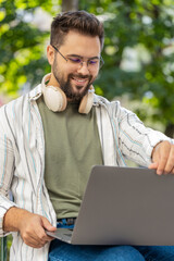 Caucasian man freelancer working online distant job with laptop sitting on city street browsing...