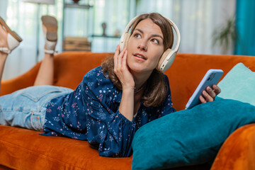 Happy Caucasian woman in wireless headphones choosing listening favorite energetic dancing music on...