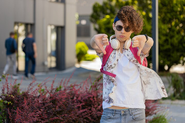 Dislike. Upset young man in sunglasses showing thumb down sign gesture, expressing discontent,...