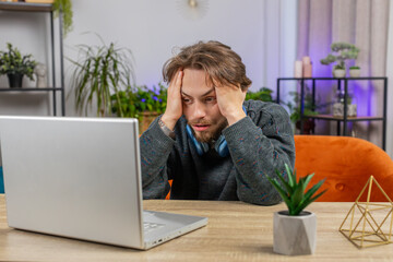 Tired Caucasian man freelancer use laptop, suffering from headache problem tension, migraine,...