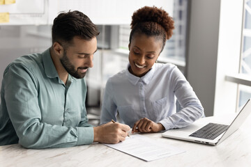 Man signing contract during meeting with young professional African woman, accepting job offer,...