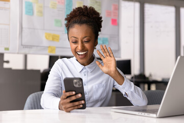 Young professional African woman greeting client, start video call using her modern smartphone...