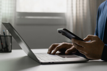 Businessman working with smartphone and laptop, digital communication, multitasking, online business concept. Man scroll social media, checks email, manages business processes, remote work from home.