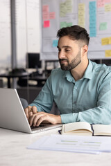 Hispanic man hold pen sit at desk with papers and personal organizer, researching information...