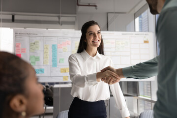 Young 30s attractive Hispanic businesswoman shaking hands with male partner or colleague start...