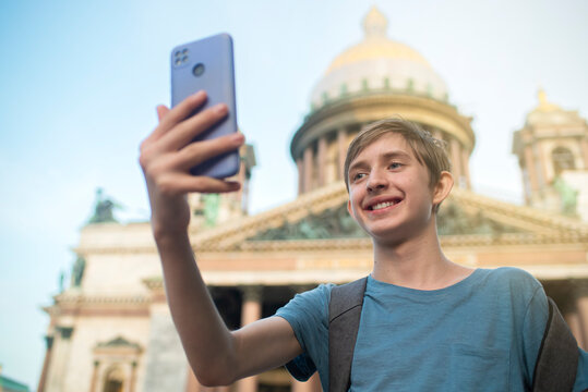 A 12-year-old boy takes a selfie on his mobile phone in front of St. Isaac's Cathedral, a landmark of St. Petersburg. - Powered by Adobe