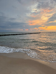 Sunset on the Baltic Sea coast in Mielno, Poland. Waves rolling onto a sandy beach under warm golden sunlight