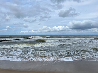 Cloudy day at the Baltic Sea, stormy waves and breakwater on the shore