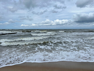 Cloudy day at the Baltic Sea, stormy waves and breakwater on the shore