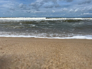 Golden sand beach with sea waves at sunset in Mielno, Baltic Sea coast, Poland