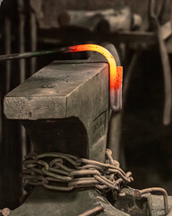A red-hot iron rod being bent on an anvil in a blacksmith's shop