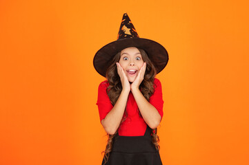 Happy Halloween. Girl witch in Halloween costume isolated on orange. Trick or treat. All Hallows...