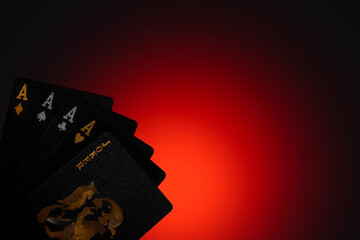 A close up of a hand of cards featuring aces and a joker against a red and black background