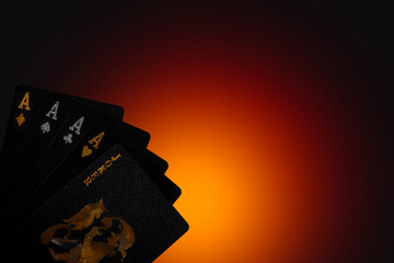A close up of a set of playing cards including three aces and a joker on a dark background