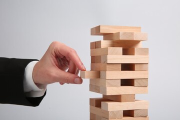 Lviv, Ukraine - December 04, 2023: Woman playing Jenga on light gray background, closeup
